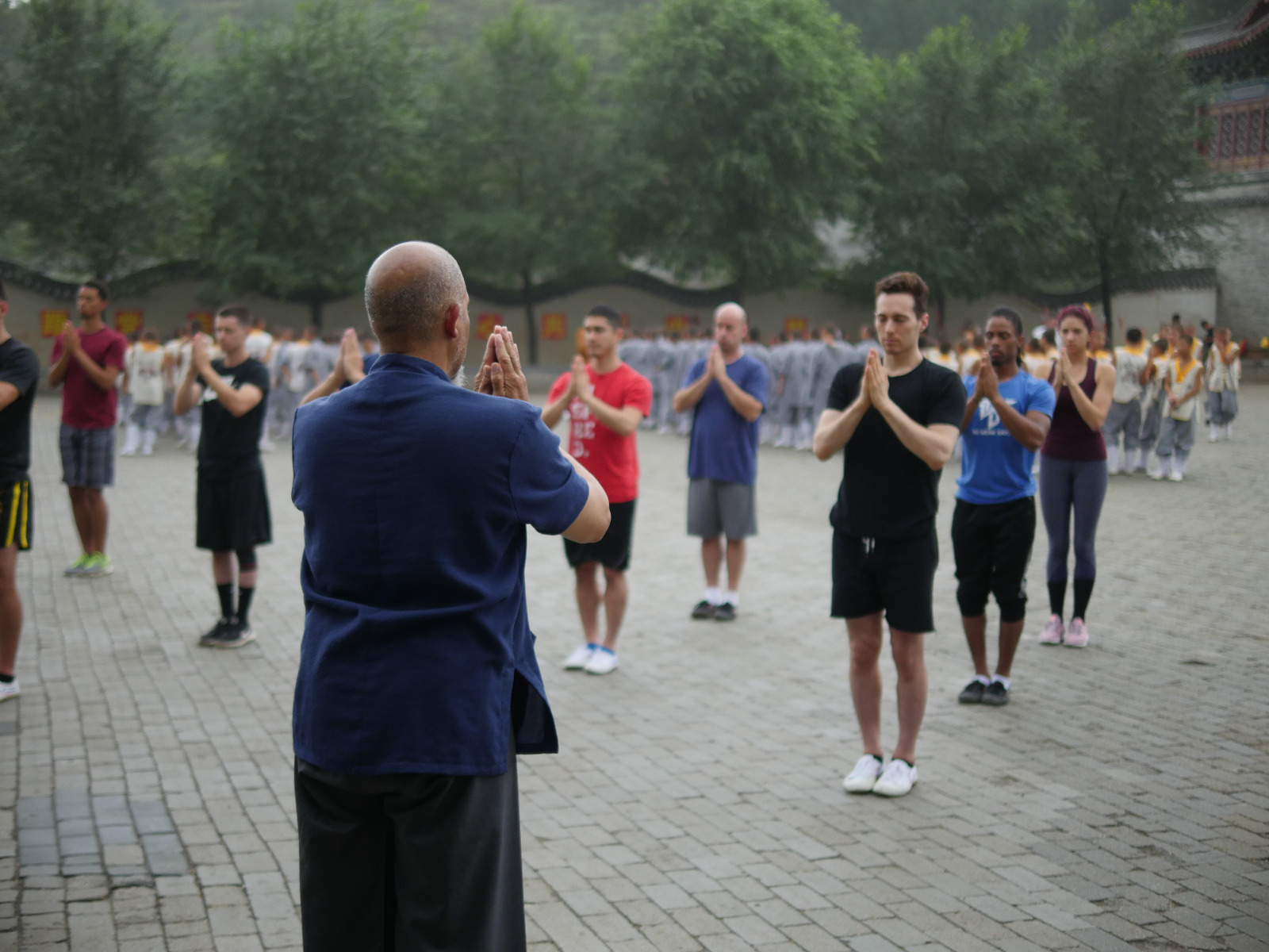 shifu in blue shirt in front of a group of people hands together